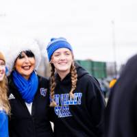 President Mantella smiles with two alumni in winter hats
